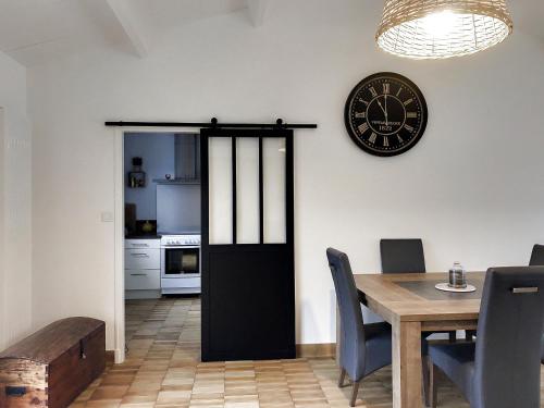 une salle à manger avec une table et une horloge au mur dans l'établissement Maison 3* proche plage, forêt et pistes cyclables avec jardin, barbecue et WIFI - FR-1-652-12, à Saint-Jean-de-Monts