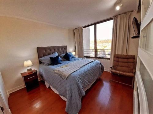 um quarto com uma cama e uma grande janela em dpto pleno centro turístico de viña del mar em Viña del Mar