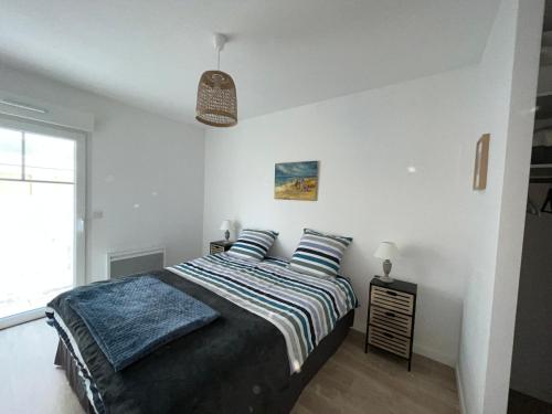 une chambre avec un lit avec des draps bleus et une fenêtre dans l'établissement Appartement T3 de 66m² avec terrasse, parking et proche jetée Thiers, centre-ville d'Arcachon - FR-1-374-209, à Arcachon