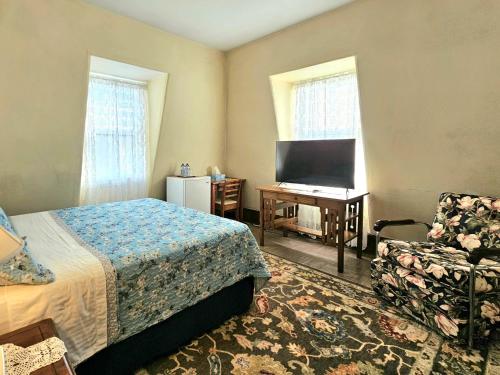 een slaapkamer met een bed, een televisie en een stoel bij Royal Hotel in Sydney