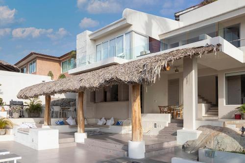 a large white house with a straw umbrella at Casa con vista a la bahía in Acapulco