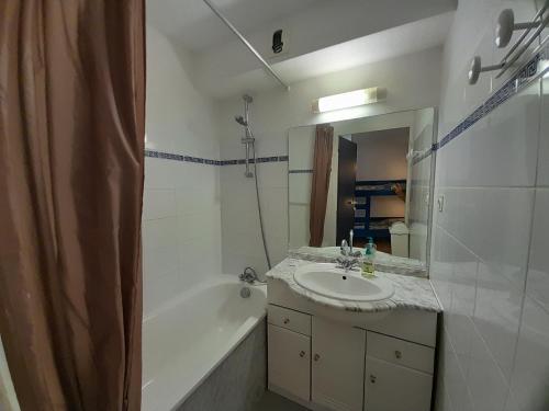 ein Badezimmer mit Waschbecken, Badewanne und Spiegel in der Unterkunft Charmant T2 avec Piscine Proche Plage et Lac à Vieux Boucau - FR-1-239-981 in Vieux-Boucau-les-Bains