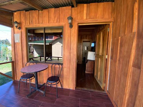 eine abgeschirmte Veranda mit einem Tisch und 2 Stühlen in der Unterkunft El Rincón de Chente in Monteverde Costa Rica