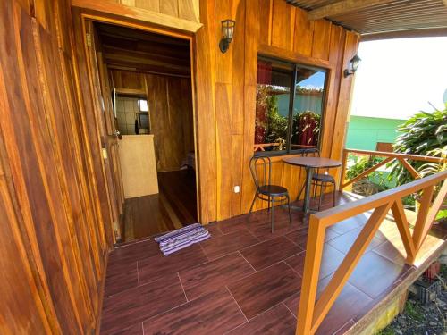 ein Holzhaus mit einem Balkon mit einem Tisch und Stühlen in der Unterkunft El Rincón de Chente in Monteverde Costa Rica