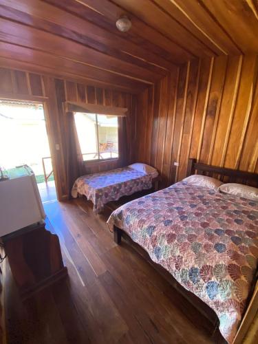 1 Schlafzimmer mit 2 Betten in einer Holzhütte in der Unterkunft El Rincón de Chente in Monteverde Costa Rica