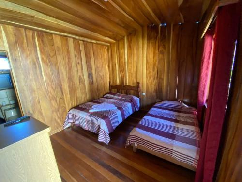 2 Betten in einem Holzzimmer mit Holzböden in der Unterkunft El Rincón de Chente in Monteverde Costa Rica