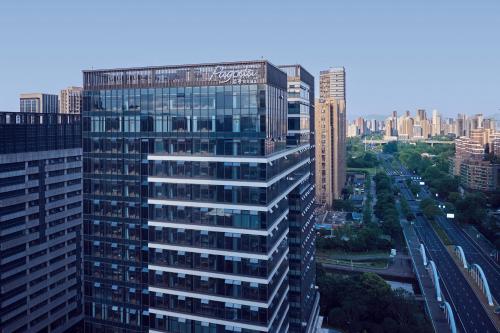 a tall building with glass windows in a city at Pagoda Hotel Hangzhou Binjiang in Hangzhou