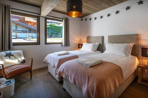 a bedroom with two beds and a chair and windows at Chalet Lula - OVO Network in Châtel