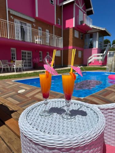 two cocktails sitting on a table in front of a pool at Pousada Pink Village in Campos do Jordão