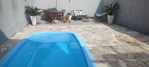 uma piscina num pátio com uma mesa e cadeiras em Casa com piscina duas quadras da praia em Guaratuba