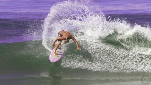 a man riding a wave on a surfboard in the ocean at Shark Town Mal Pais in Santa Teresa Beach