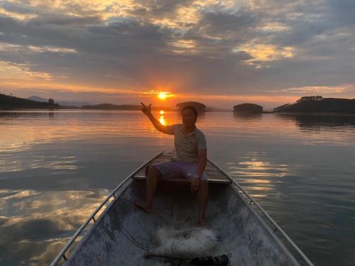 a woman sitting in a boat on the water at sunset at Lakeview Homestay Vu Linh in Yen Bai