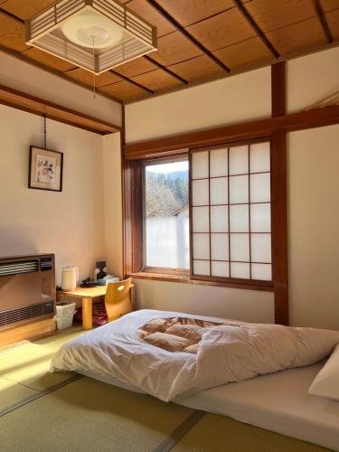a bedroom with a bed in a room with a window at AKANE Hostel あかね天然温泉旅館 in Yuzawa