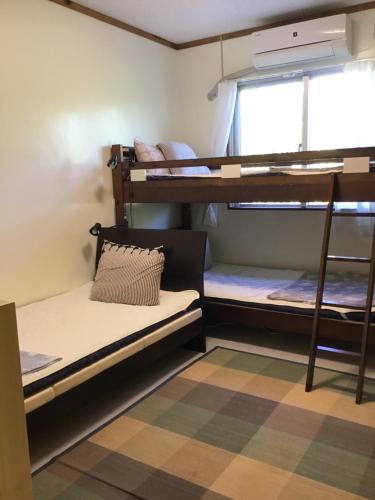 a dorm room with bunk beds and a window at Shimaotoya in Iriomote