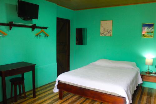 a bedroom with a bed and a desk and a television at Posada Río Celeste La Amistad in Rio Celeste