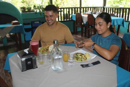 a man and a woman sitting at a table with a plate of food at Posada Río Celeste La Amistad in Rio Celeste