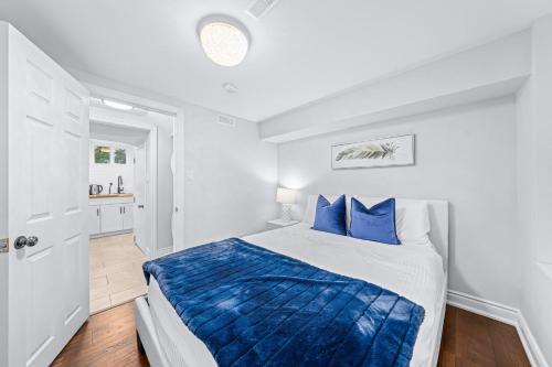 ein weißes Schlafzimmer mit einem Bett mit blauen Kissen in der Unterkunft 1BR+ Sofa Bed & Cozy Fireplace in Barrie