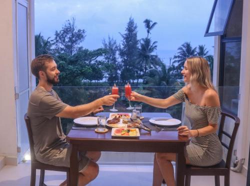 a man and woman sitting at a table with drinks at Mzion Hotel Weligama in Weligama