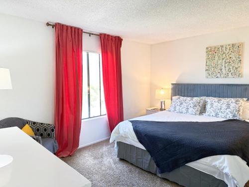 1 dormitorio con 1 cama con cortinas rojas y ventana en Comfort Apt Rowland Heights en Rowland Heights