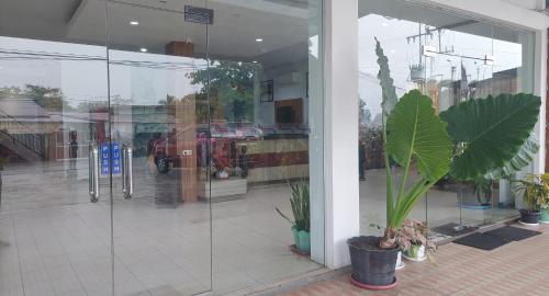Ladja Hotel Sintang في Sintang: واجهة متجر بأبواب زجاجية ونبات خزف