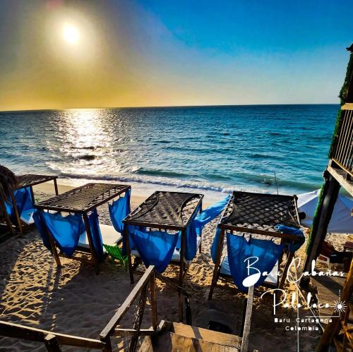 um grupo de cadeiras e mesas na praia em Palos Locos Baru em Cartagena das Índias