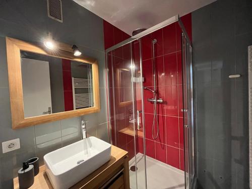 La salle de bains est pourvue d'un lavabo et d'une douche avec du carrelage rouge. dans l'établissement Superbe appartement rénové aux Gets, proche centre et pistes, balcon, casier à skis - FR-1-623-155, aux Gets
