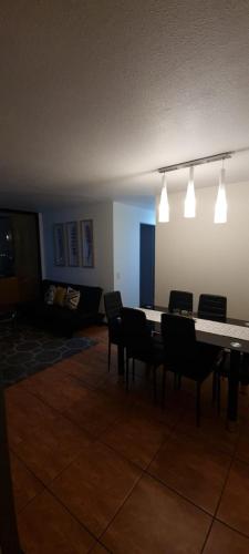 una sala da pranzo con tavolo, sedie e luci di Amplió, cómodo y amoblado departamento, La Florida a Santiago