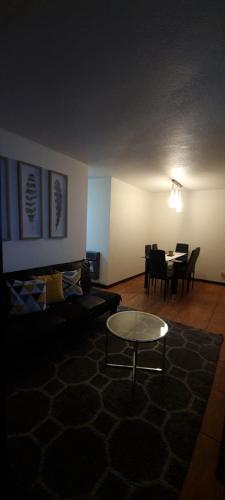 sala de estar con mesa y sofá en Amplió, cómodo y amoblado departamento, La Florida, en Santiago
