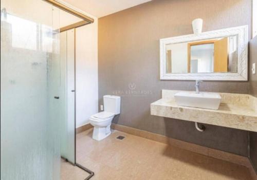 ein Badezimmer mit einem Waschbecken, einem WC und einem Spiegel in der Unterkunft Linda casa Assunção com Piscina Aquecida in Porto Alegre