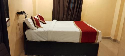 a bed with red and white sheets and pillows at The Royal Inn in Visakhapatnam