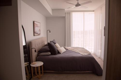 a bedroom with a bed with a ceiling fan and a window at Amara at Solaris in Forster