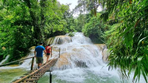 two people standing on a bridge in front of a waterfall at Inh La Home Pu Luong in Pu Luong