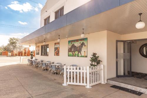 a building with chairs and a white fence in front of it at Sportsmens Club Hotel in Wagga Wagga