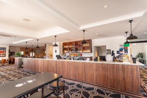 bar w restauracji ze stołami i krzesłami w obiekcie Sportsmens Club Hotel w mieście Wagga Wagga