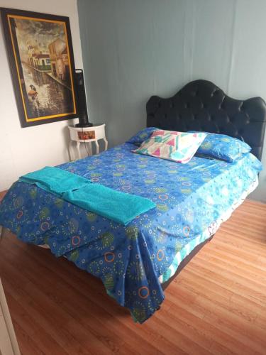 a bed with a blue comforter on a wooden floor at Apartamento Sur Conjunto Cerrado in Cali