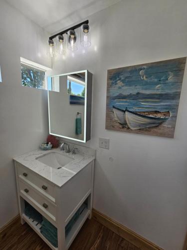 un baño con lavabo y una pintura de un barco en SeaSide Lake-Front Cottage en Madison