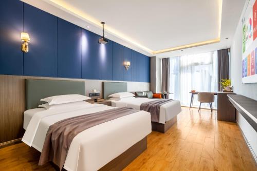 2 łóżka w pokoju hotelowym z niebieskimi ścianami w obiekcie Suberun Hotel - Jinyang Street w mieście Taiyuan