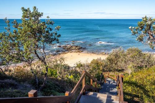 a staircase leading to a beach with the ocean at Papillon Coolum in Coolum Beach