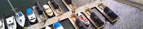 eine Gruppe von Booten, die auf einem Dock im Wasser geparkt sind in der Unterkunft Boathouses - Overnat på vandet ved Limfjorden in Vinderup