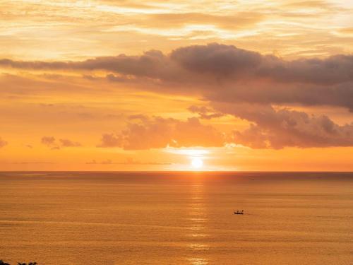 a boat in the ocean at sunset at Novus Jiva Anyer in Anyer
