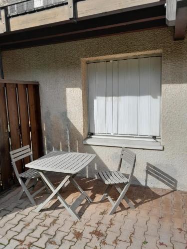 a picnic table and two chairs next to a building at Challes les eaux in Challes-les-Eaux