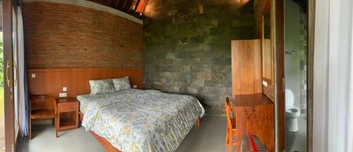 a bedroom with a bed and a brick wall at Anandinii River Lodge in Sidemen