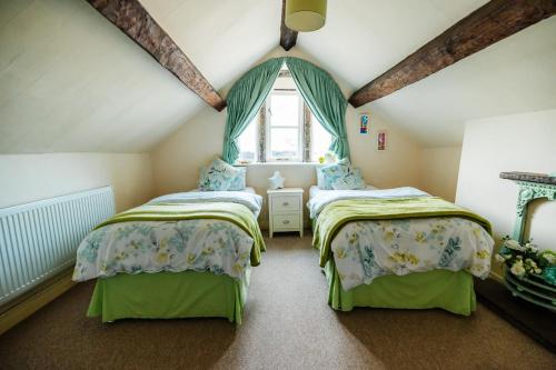 two beds in a attic room with a window at Langs Hall in Leyland