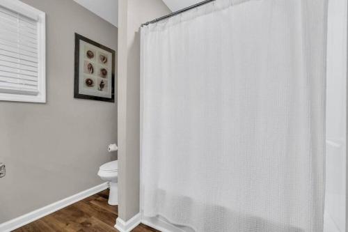 a white bathroom with a toilet and a shower curtain at Seaside Cottage: A 'MyShoreCottage' Property in Seaside Heights