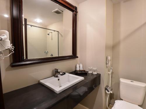 a bathroom with a sink and a toilet and a mirror at The Rich Jogja Hotel in Yogyakarta