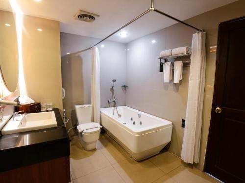 y baño con bañera, aseo y lavamanos. en The Rich Jogja Hotel, en Yogyakarta