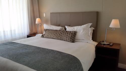 a bedroom with a large white bed with two lamps at Lagoon Beach Hotel & Spa in Cape Town