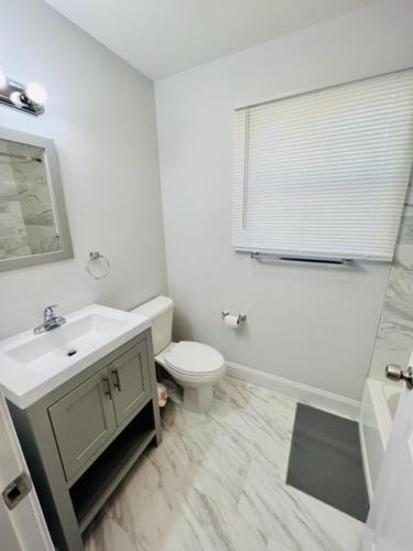 a white bathroom with a sink and a toilet at Cozy & Deluxe Apartment - EZ Access to NYC in Newark