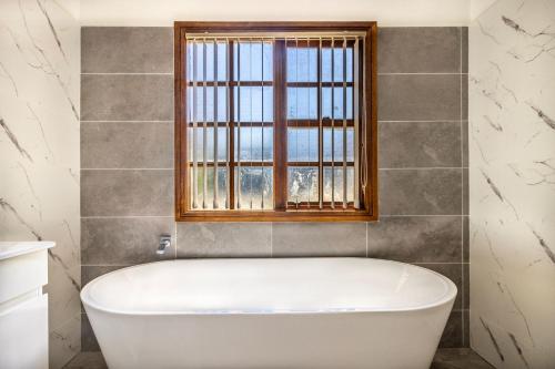 a bath tub in a bathroom with a window at Swan Lake Escape in Sussex inlet