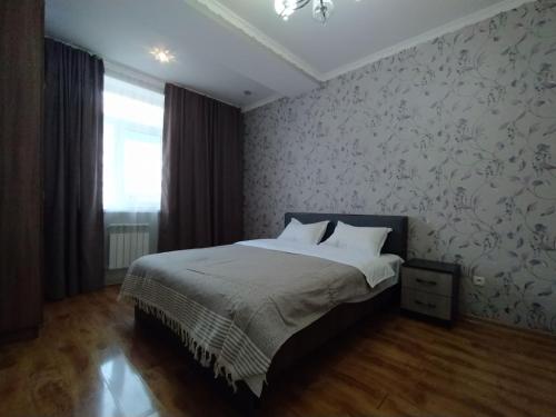 比什凱克的住宿－AURA on Isanov street 118，一间卧室配有一张带白色床单和花卉壁纸的床